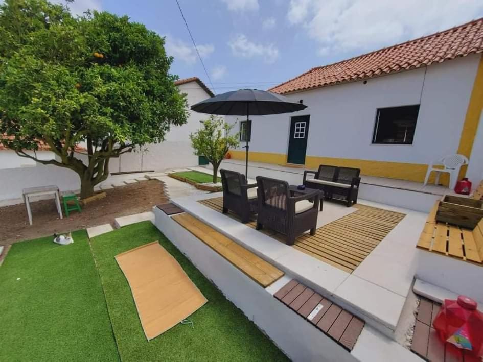 eine Terrasse mit Sonnenschirm und Rasen in der Unterkunft A casa da Laranjeira in Vale Covo