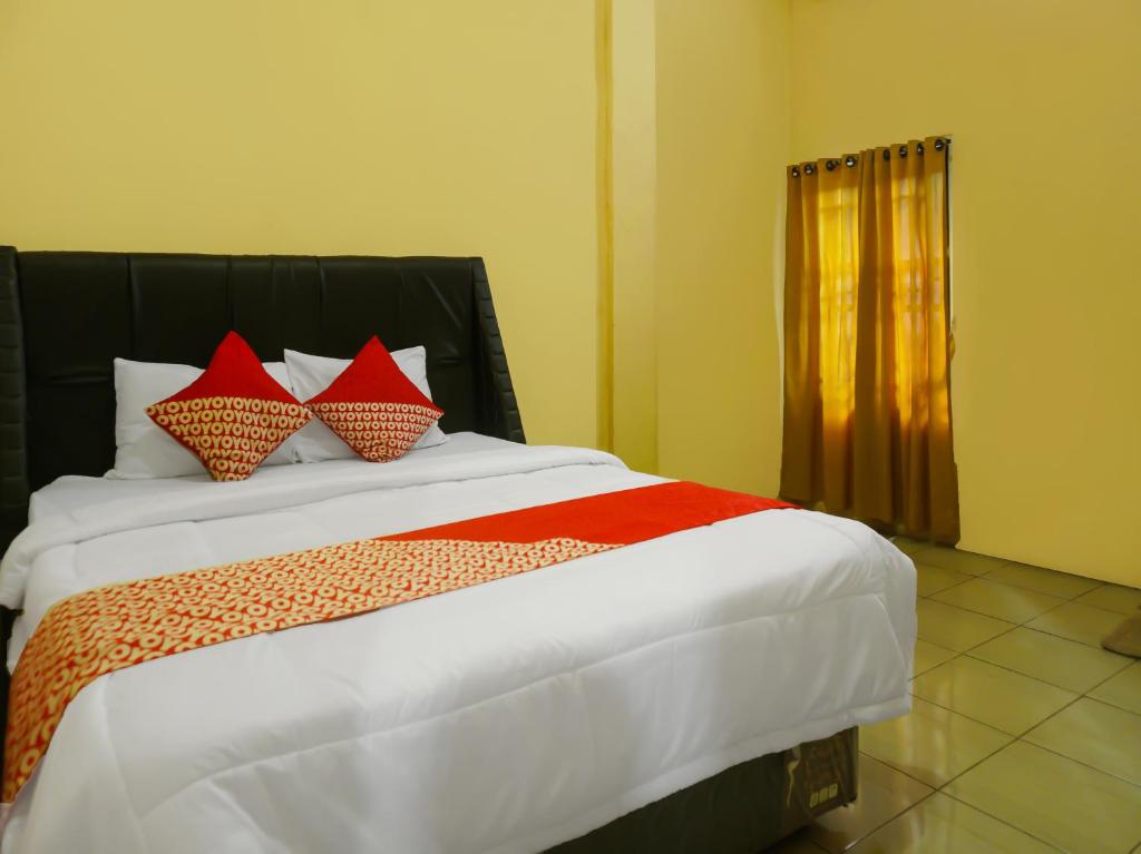 ein Schlafzimmer mit einem großen Bett mit roten Kissen in der Unterkunft OYO 92377 Wisma Melyro Syariah 