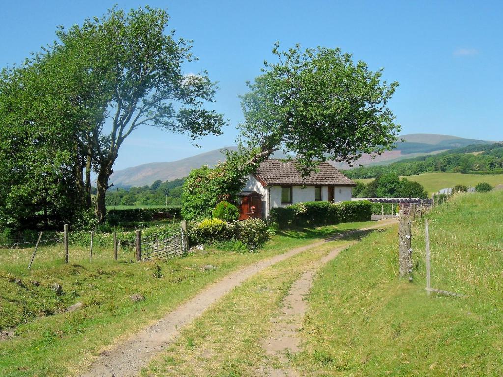 eine unbefestigte Straße, die zu einem kleinen Haus auf einem Feld führt in der Unterkunft Gean Cottage in Powmill