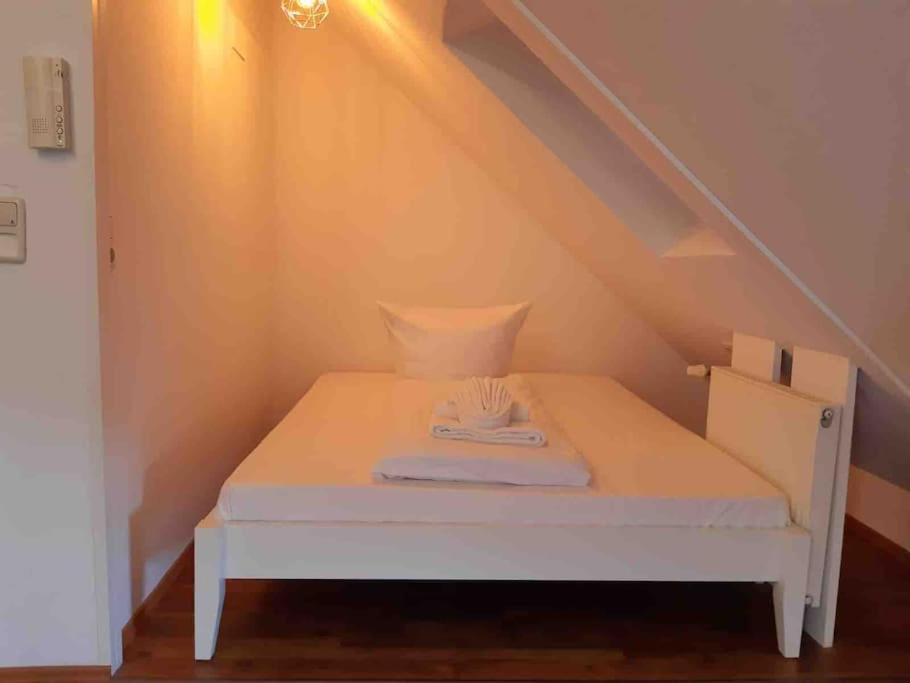a small white bed in a room with stairs at Apartment Blattgold in Schwabach