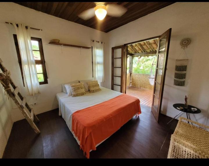 1 dormitorio con 1 cama con manta naranja en Goura House Ilhabela, en Ilhabela