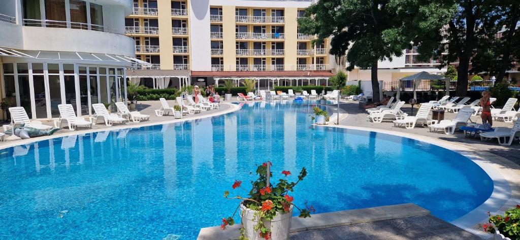 a large swimming pool with chairs and a hotel at Sun Palace Suites in Sunny Beach