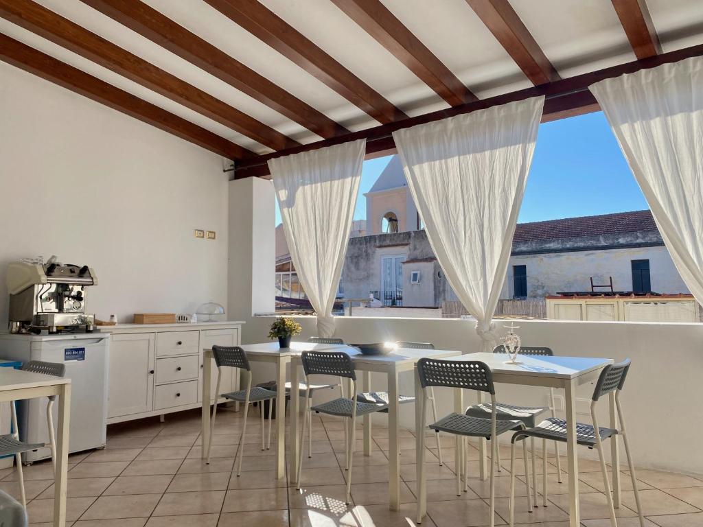 kuchnia z białymi stołami i krzesłami oraz oknami w obiekcie Mamamia #Lipari w mieście Lipari