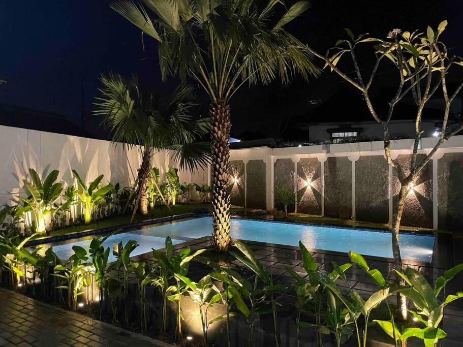 ein Pool mit Palmen und Lichtern in der Nacht in der Unterkunft Dhanis House 7 Bedroom Villa in Cibanawak