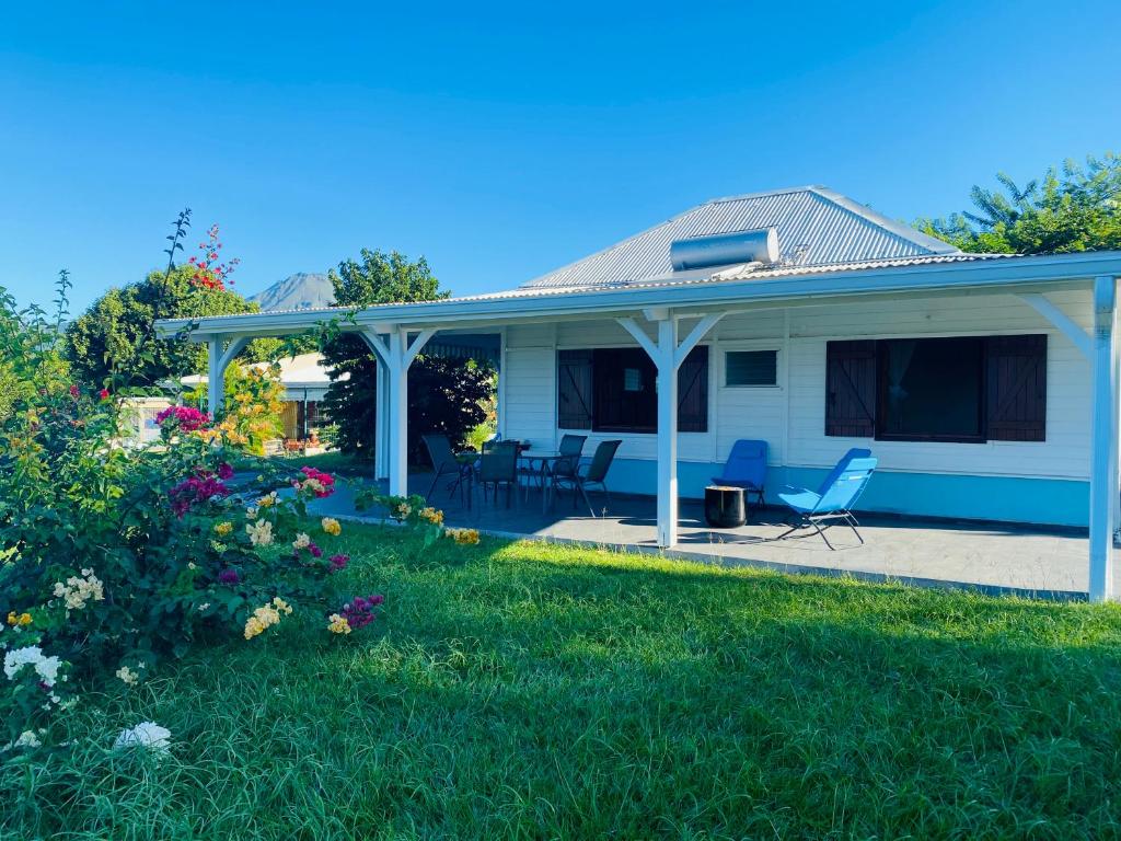 una casa blanca con sillas y flores en el patio en Villa Créole vue sur mer des Caraïbes, en Le Carbet