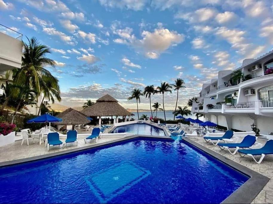 einen Pool im Resort mit Stühlen und Sonnenschirmen in der Unterkunft Hermoso condominio en Bahía Manzanillo in Manzanillo