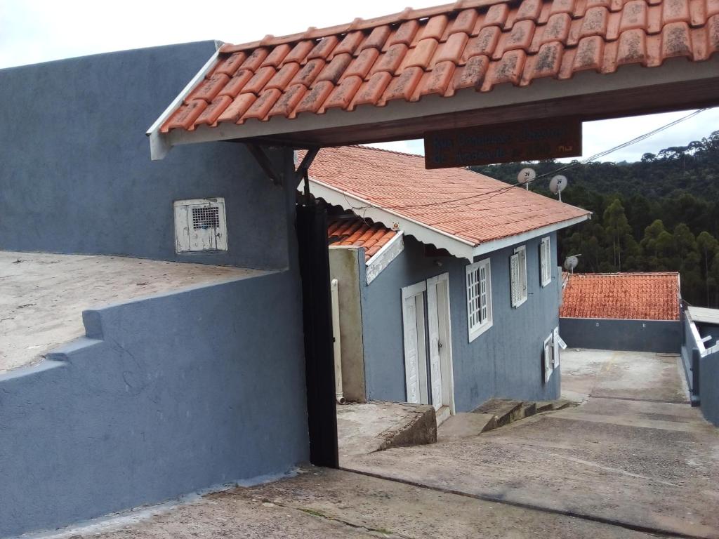 ein blaues Haus mit rotem Dach und einer Veranda in der Unterkunft Cantinho aconchegante in Campos do Jordão