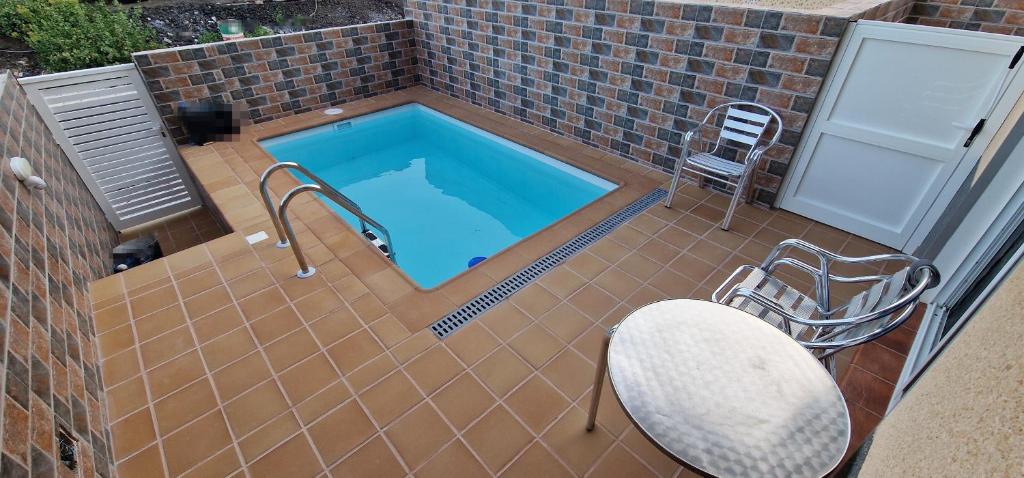 una piscina con una mesa y una silla en un patio en VV EL OASIS en Tamaduste