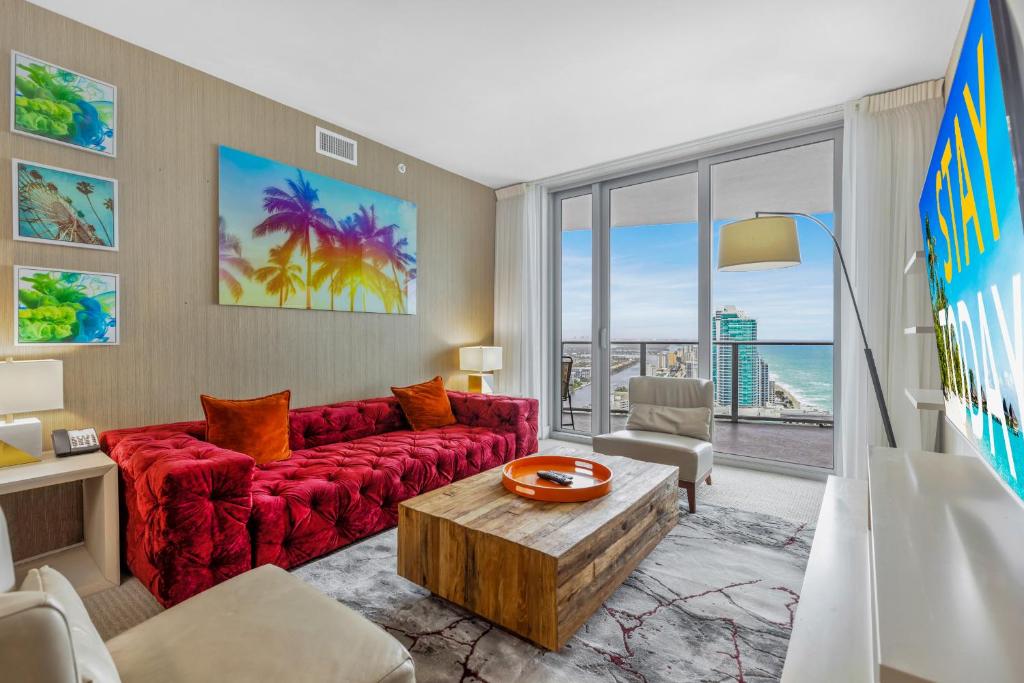 a living room with a red couch and a view of the ocean at EXCLUSIVE RESORT - OCEANFRONT 2BD 2BA CONDO, HiGH FLOOR, ROOFTOP POOL AND HOT TUB, STEPS TO BEACH in Hollywood