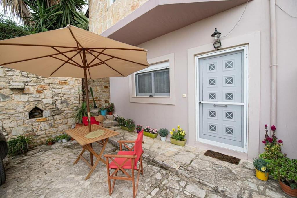 a patio with a table and an umbrella next to a garage at Landscape Apartment in Kallithéa
