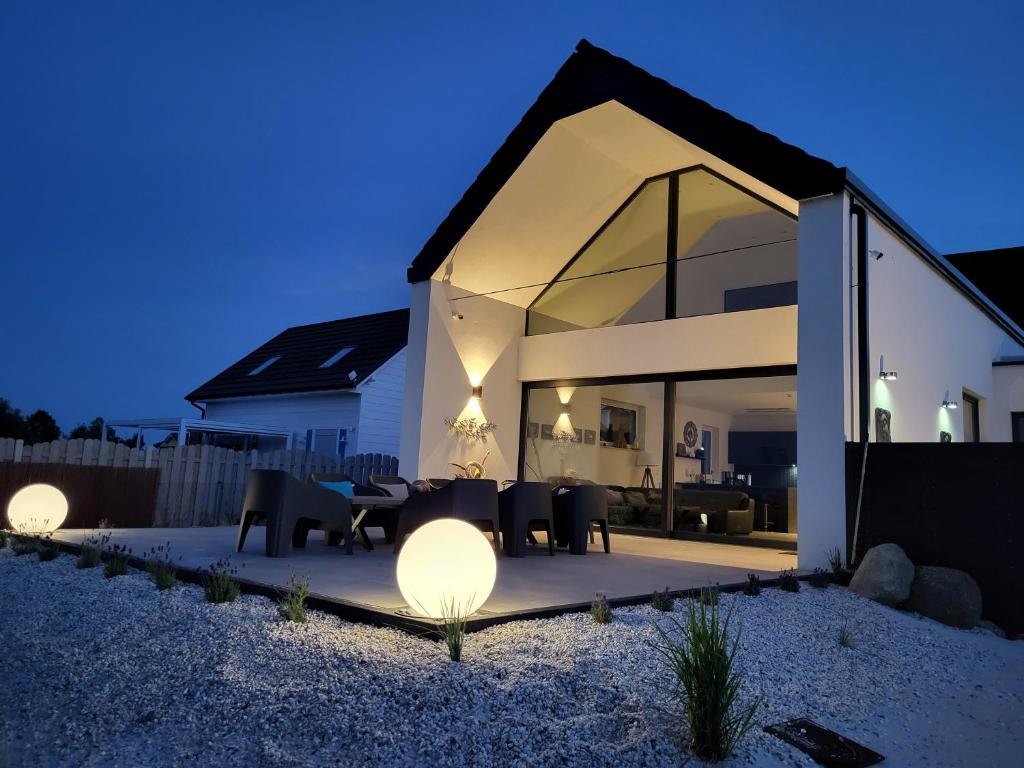 Casa con paredes de cristal y patio con mesas y sillas. en Robson Beach I Sauna, Jacuzzi en Międzywodzie