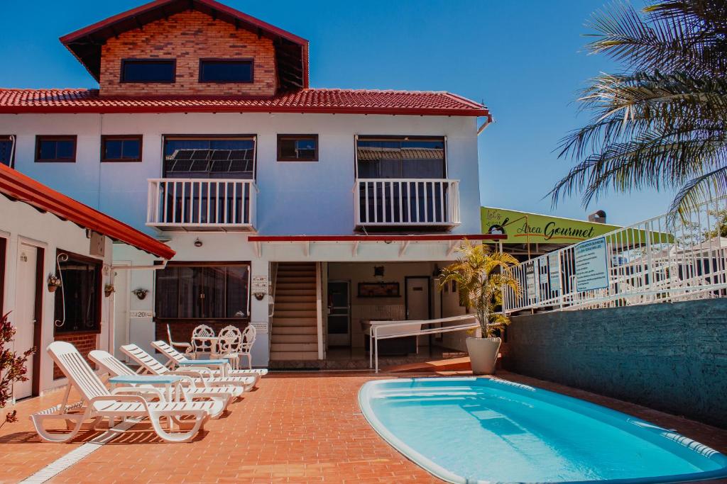 uma casa com piscina em frente a uma casa em Pousada Iguassu Charm Suites em Foz do Iguaçu