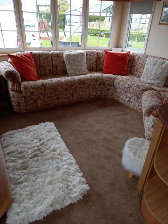 a couch in a living room with red and white pillows at Adorable Caravan in Western Lakes in Workington