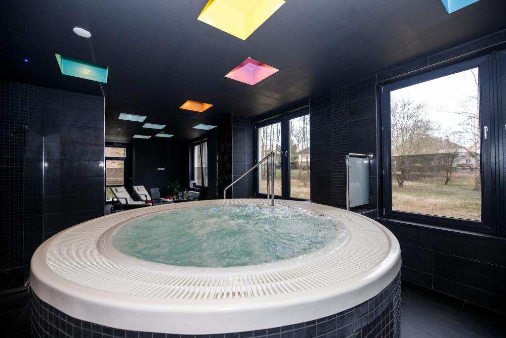 ein Bad mit einer großen Badewanne in einem Zimmer mit Fenstern in der Unterkunft Parkhotel Carlsbad Inn in Karlsbad