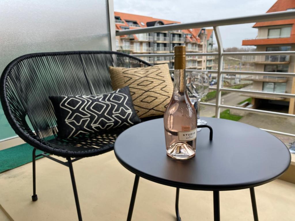 butelka wina leżąca na stole na balkonie w obiekcie Petit plage Nieuwpoort-Bad w mieście Nieuwpoort