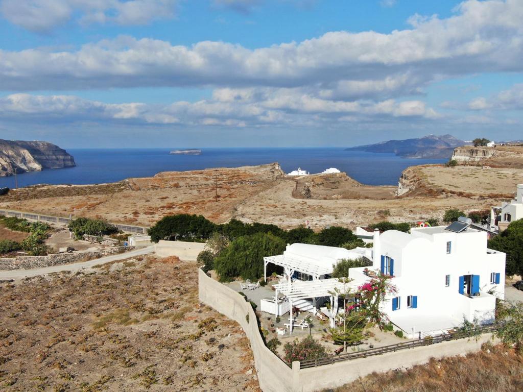 een groep witte gebouwen op een heuvel met de oceaan bij Arcana Santorini Villas, An Authentic Cycladic Experience in Akrotiri