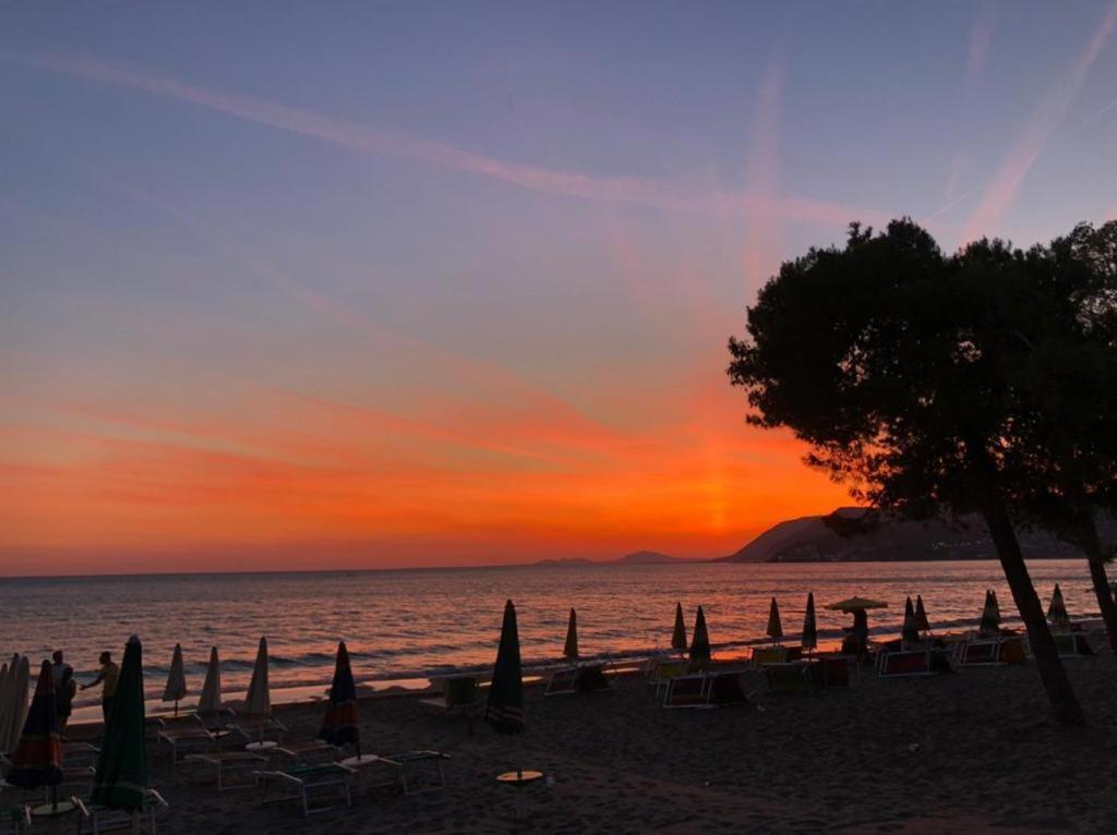 un grupo de sombrillas y sillas en una playa al atardecer en Iris apartaments, en Sakës