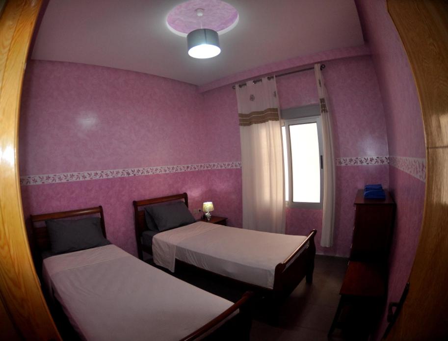 a pink room with two beds and a window at Coopérative Village Jbel Moussa du Tourisme in Rcham
