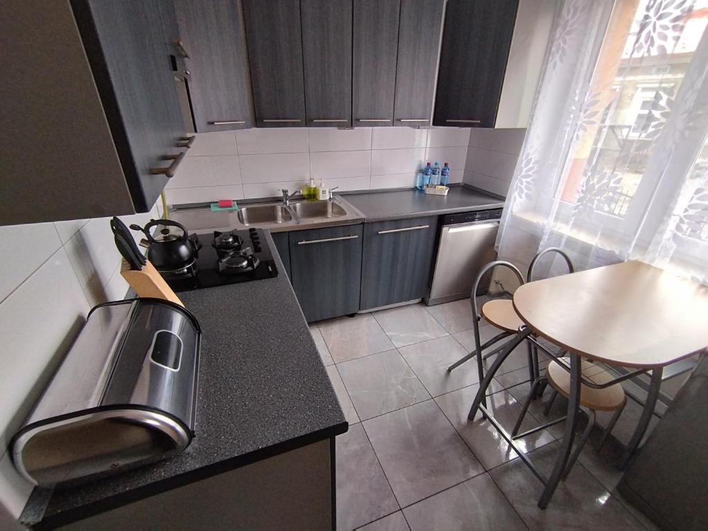 uma pequena cozinha com uma mesa e um lavatório em Apartament przy dworcu w Sanoku em Sanok