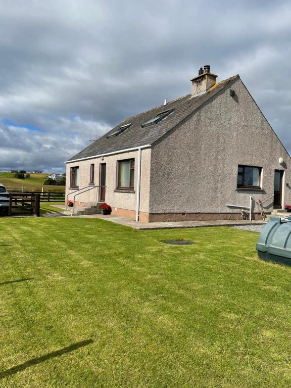 a large building with a grass yard in front of it at Self Catering house with lovely sea views, 44 Back in Vatsker