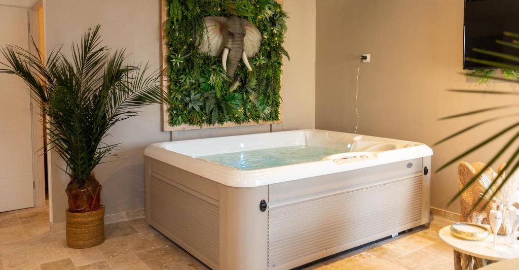 uma banheira de hidromassagem num quarto com uma planta em L’Amazonie Gite Spa em Beutin