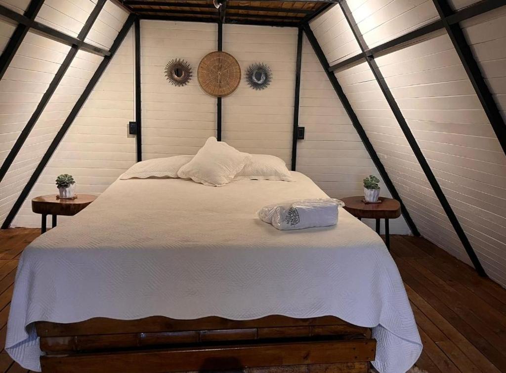 una camera da letto con un grande letto bianco con due tavoli di Entre Verdes Hotel & Glamping a Medellín
