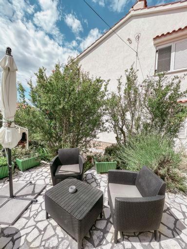 a patio with chairs and a table and an umbrella at Apartman Ponte Martini in Punat