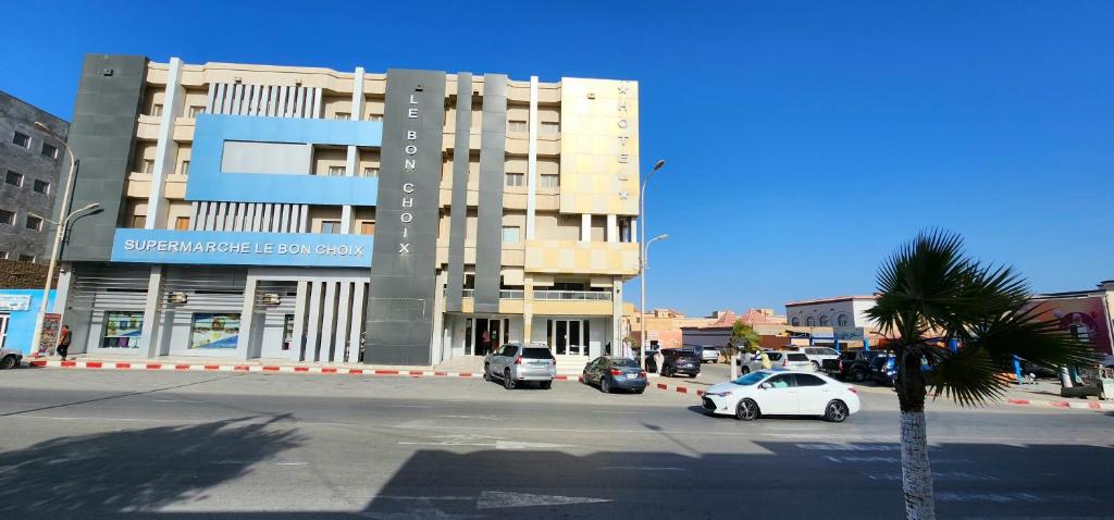 um grande edifício com carros estacionados em frente em HOTEL LE BON CHOIX em Nouadhibou