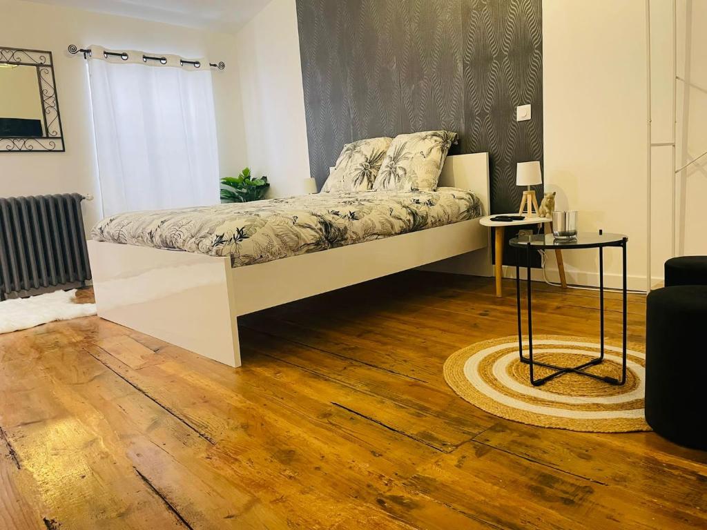 a bed in a room with a wooden floor at Les Dames Jeannes in Jarnac