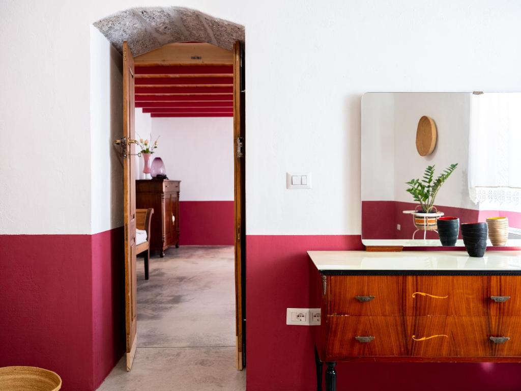 a kitchen with red and white walls and a doorway at Binzas betzas Agriturismo in Sedilo