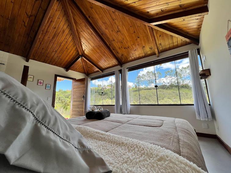 um quarto com uma cama grande e janelas grandes em Chalé Lírio do Campo em Ouro Preto