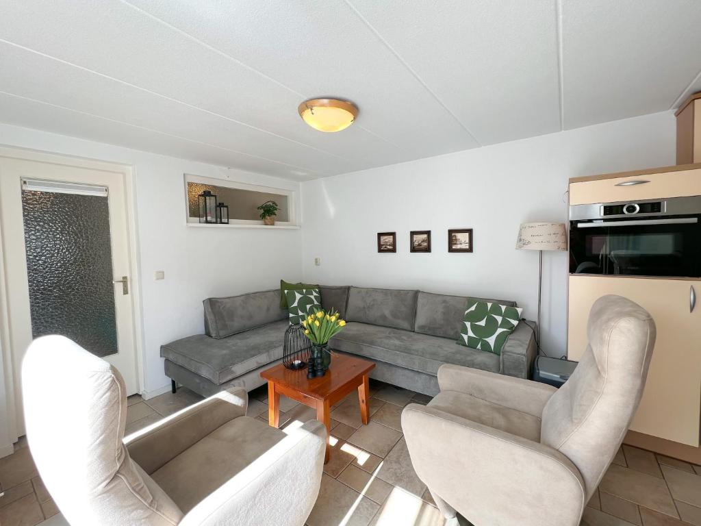 a living room with couches and a table at Gelijkvloers Vakantieappartement 150m van Strand Egmond aan Zee in Egmond aan Zee