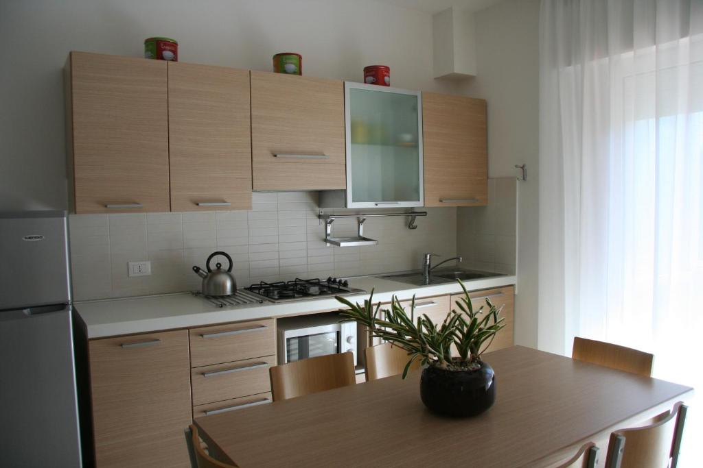 una cucina con armadi in legno e un tavolo con una pianta in vaso di Appartamenti Aquamarina a Lido di Jesolo