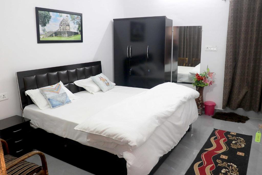 1 dormitorio con 1 cama grande con sábanas y almohadas blancas en Khajuraho Glory Homestay en Khajurāho