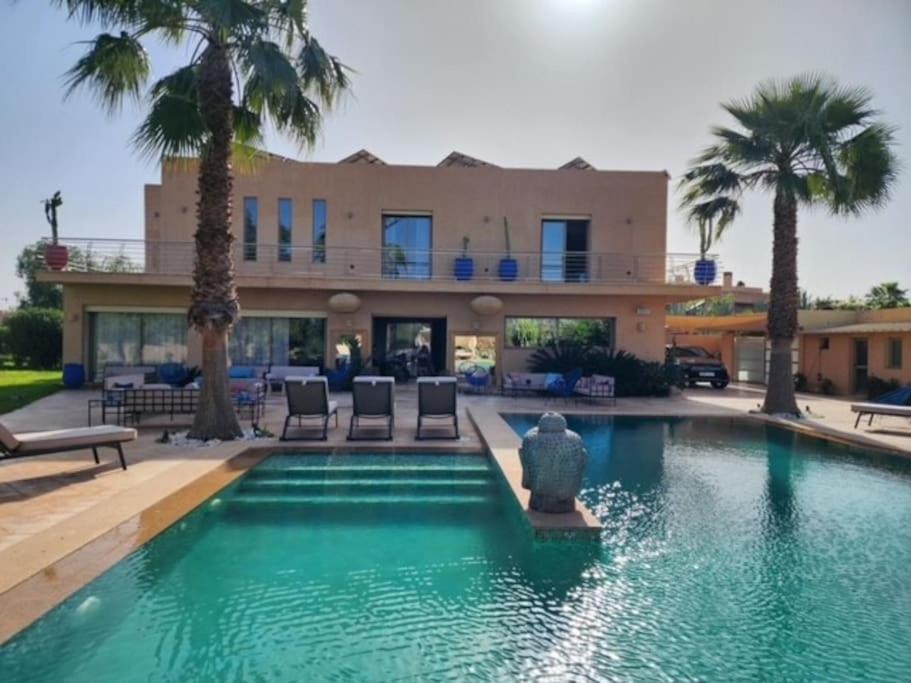 a house with a swimming pool and palm trees at Villa de rêve à Marrakech in Marrakesh