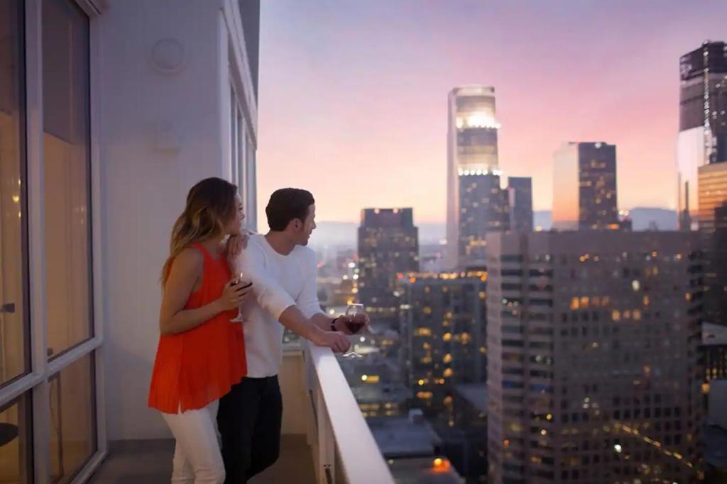 Ein Mann und eine Frau stehen auf einem Balkon in einer Stadt in der Unterkunft Level Downtown LA South Olive in Los Angeles