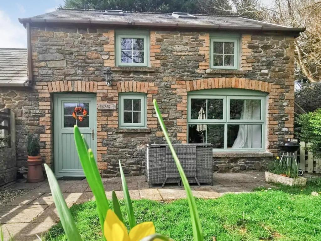 Casa de piedra con puerta verde y ventanas en Ystabl en Llannon