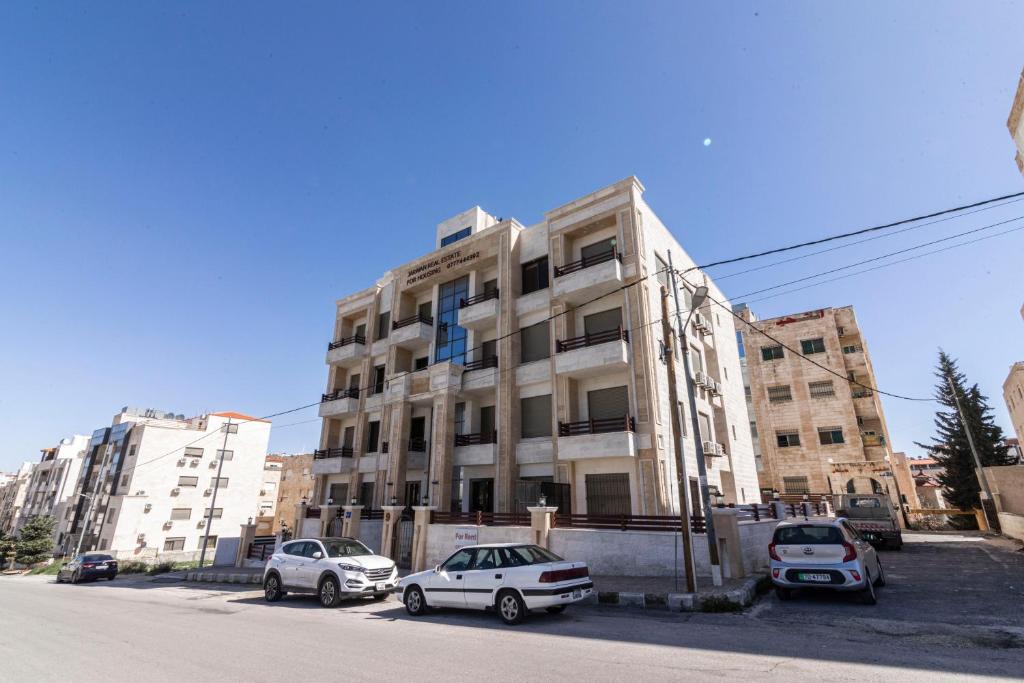 tres coches estacionados frente a un edificio en Amman Sun Apartments, en Ţāb Kirā‘