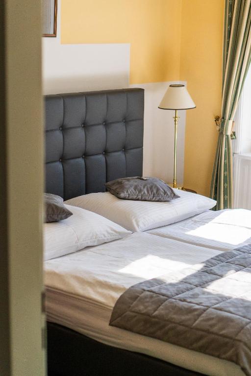 sypialnia z 2 łóżkami z zagłówkiem i lampką w obiekcie Hotel Bergwirt Schönbrunn w Wiedniu