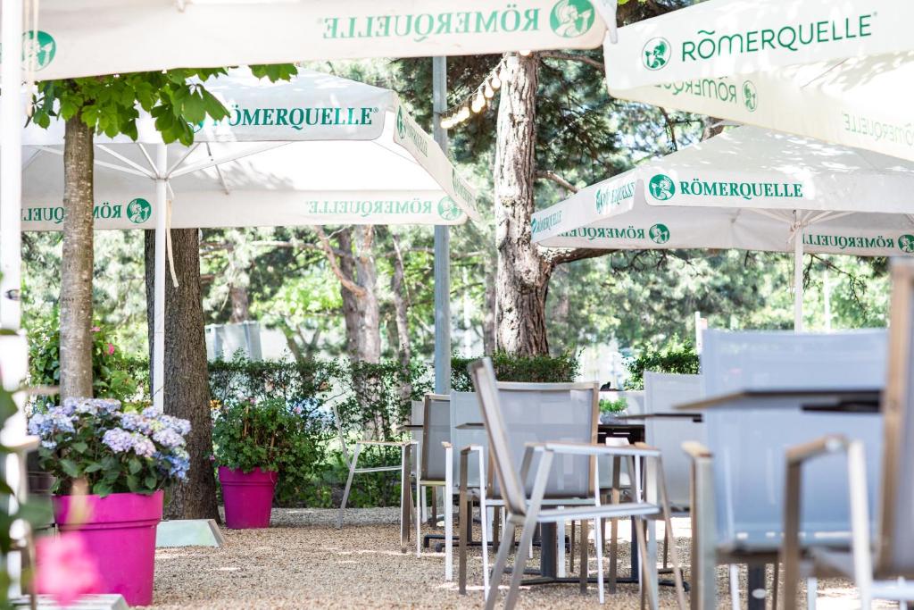 grupa stołów i krzeseł pod parasolami w obiekcie Hotel Bergwirt Schönbrunn w Wiedniu