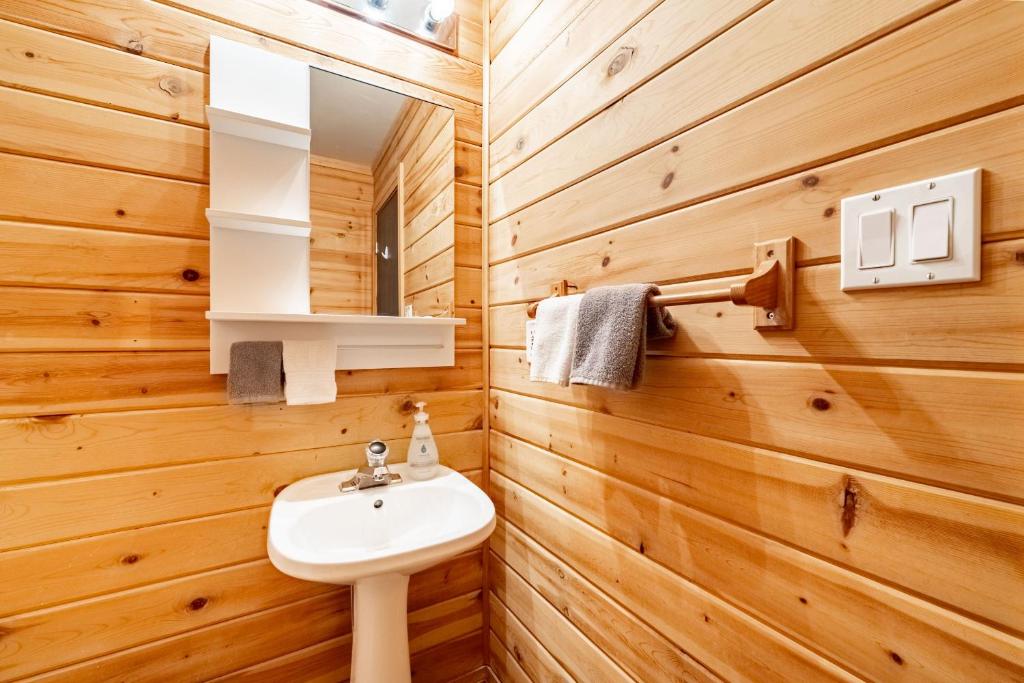 baño con lavabo blanco y paredes de madera en Oakview Lodge & Marina, en Algonquin Highlands