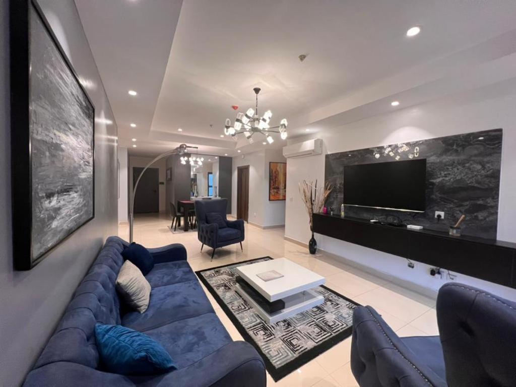een woonkamer met een blauwe bank en een tv bij Classic 2-bedroom condo in Lagos