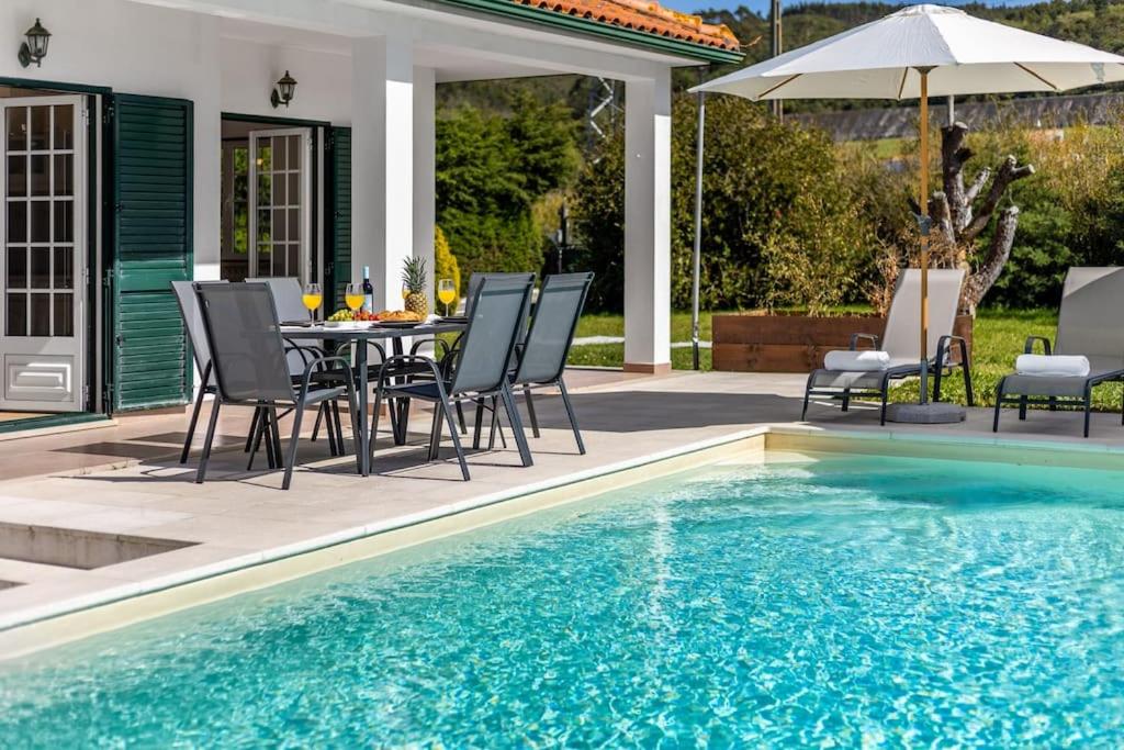 un patio con tavolo e sedie accanto alla piscina di Villa Coral - Private Heated Pool & Hot tub a Famalicão