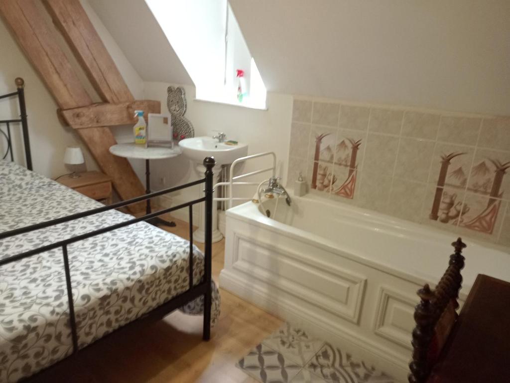 a bathroom with a tub and a sink and a bed at Bergerie Bracquetuit in Bracquetuit