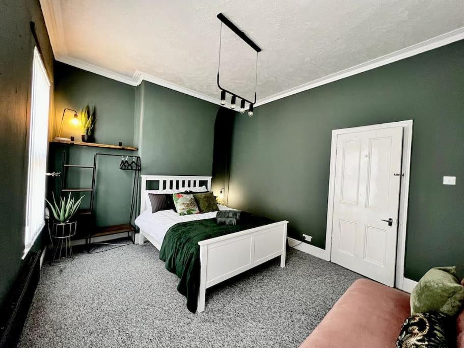 een slaapkamer met een bed en een groene muur bij *Hot* Fantastic 3/4 Beds Town House in Anfield Stadium in Liverpool