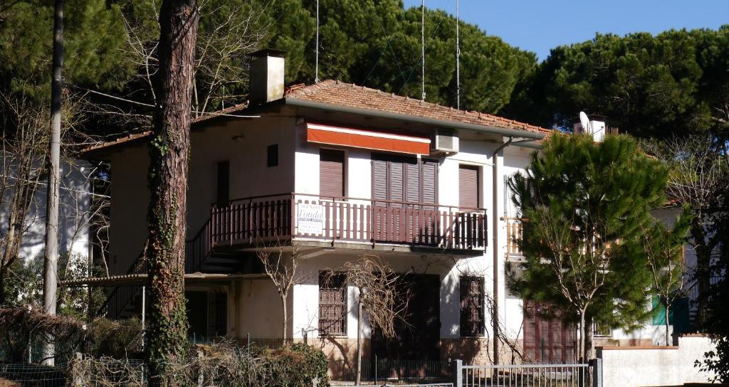 una casa bianca con balcone e alberi di Villetta 4B a Lido degli Estensi