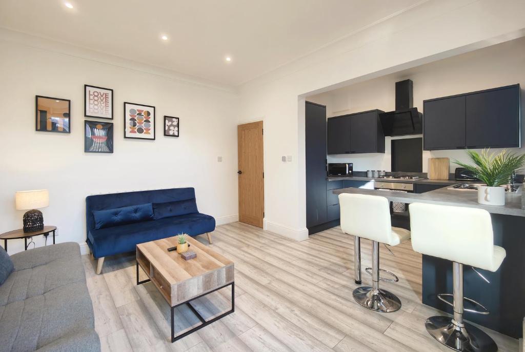 a living room with a blue couch and a kitchen at Lindsay House - South Manchester Stylish Townhouse With Free Parking in Manchester