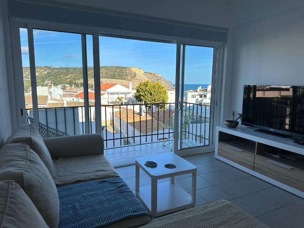 een woonkamer met een bank, een tv en een balkon bij Casa Sea Love Luz in Luz