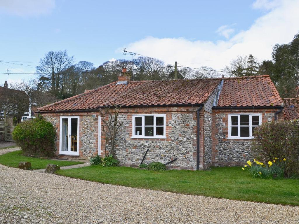 StiffkeyにあるManor Cottageの白い窓と芝生のある小さなレンガ造りの家