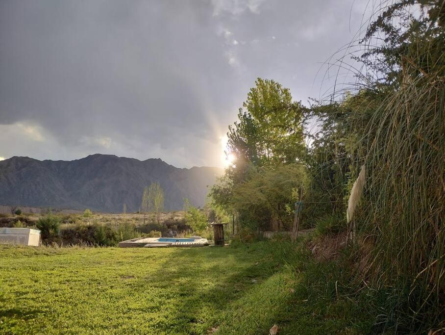 un campo de hierba con el sol en el fondo en Vista los Andes en Cacheuta